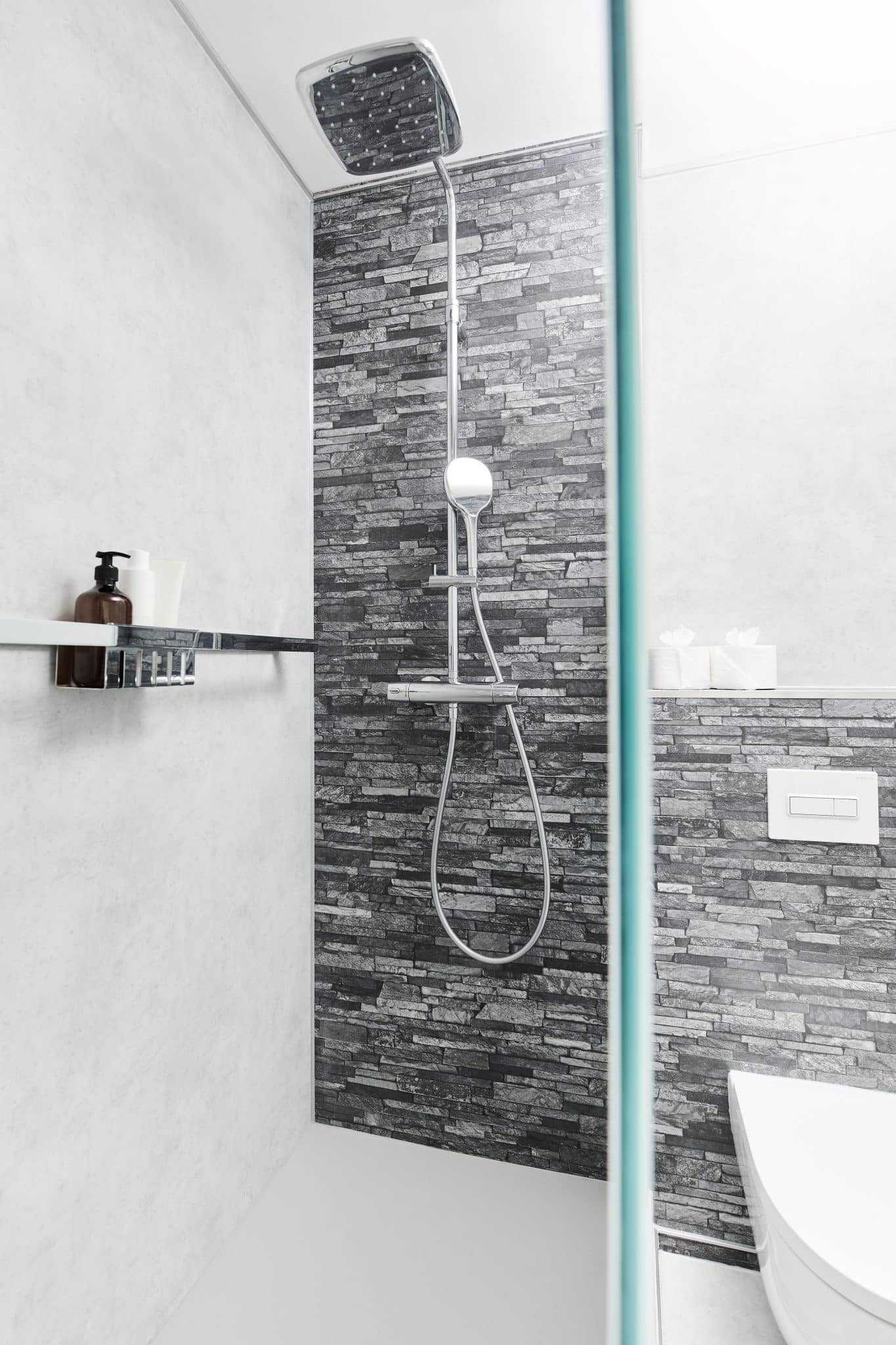 Dusche mit Ablage für Duschgel neben einem Wand-WC